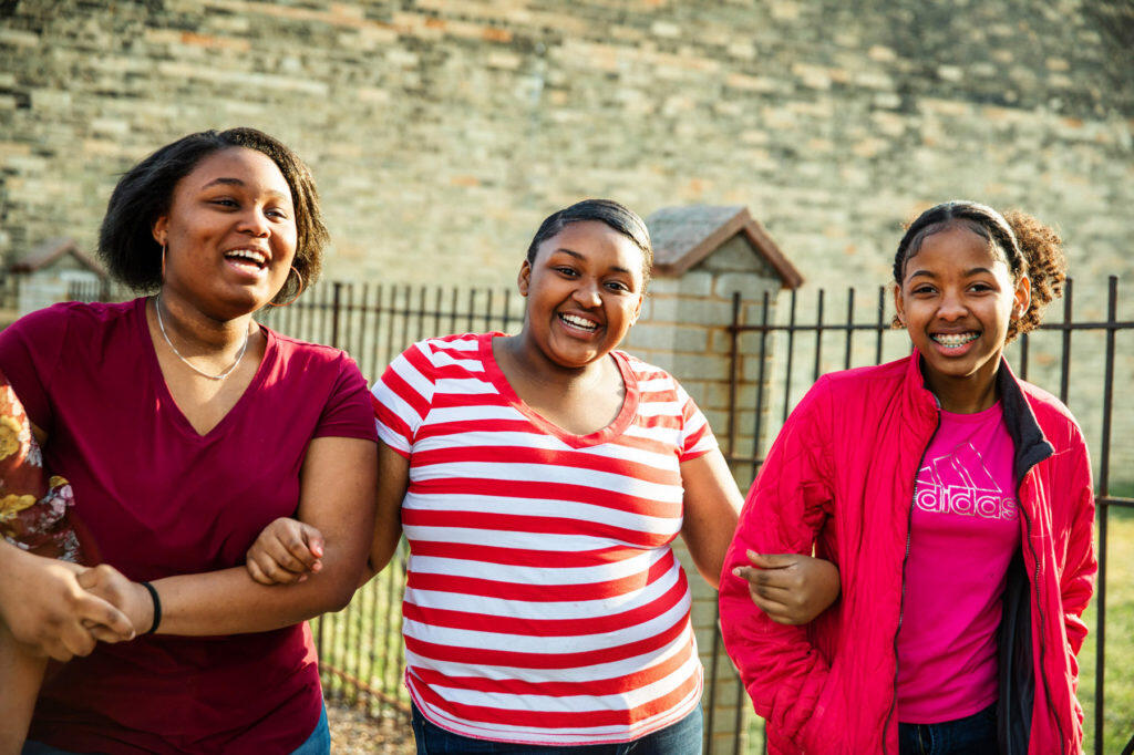 Three young women locking arms and smiling for a photo