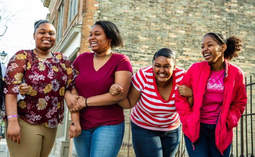 Four young women lock arms and pose for a photo