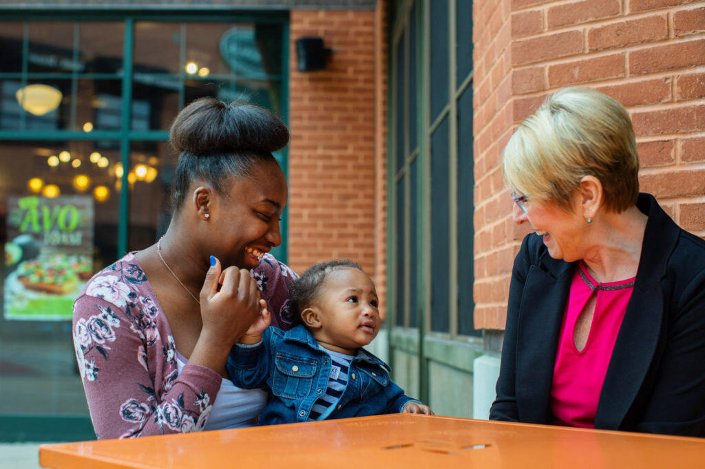 Essence and Carrie laugh as they play with Essence's baby