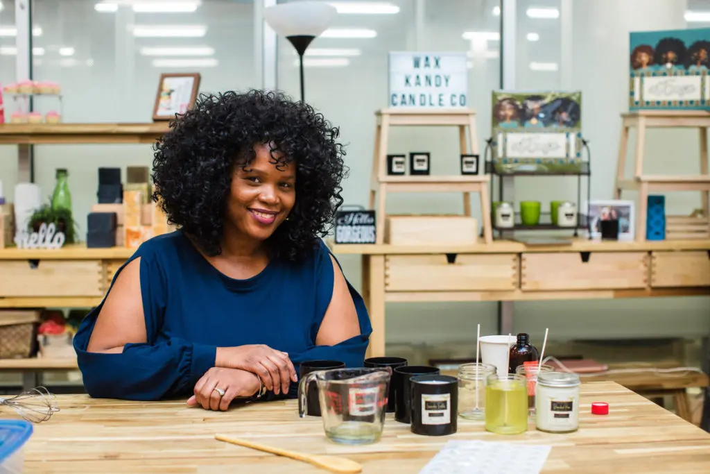 Kimberly Sumpter poses at a table with candle-making supplies on the table