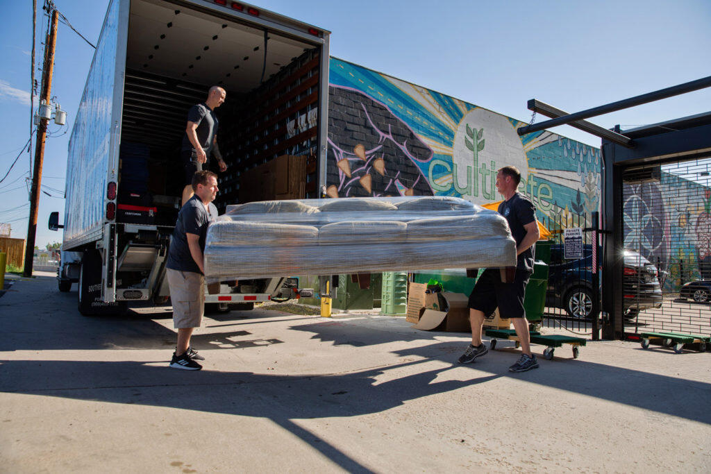 Two men load a couch into a moving truck