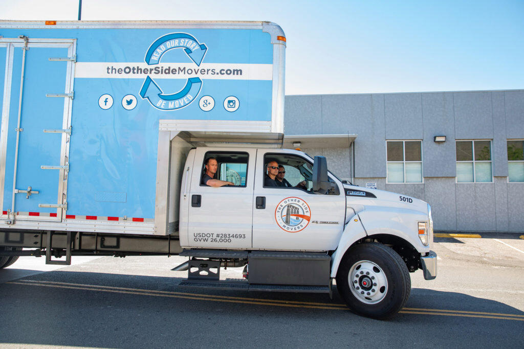 Three men in an the Other Side Movers truck