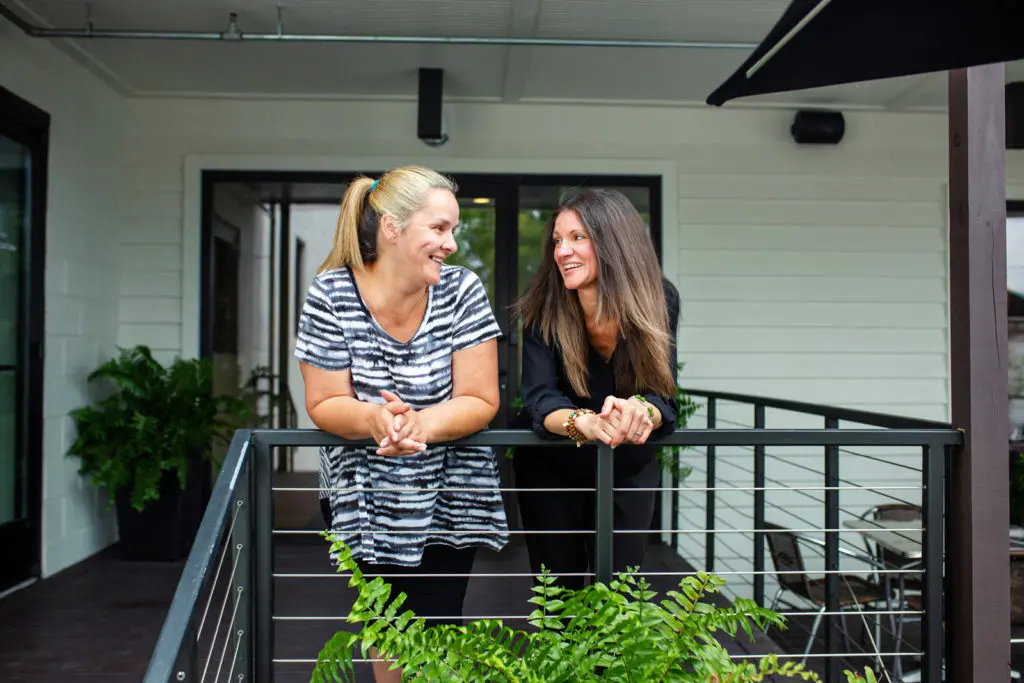 Shelia McClain and Keri Seay talk leaning over a railing