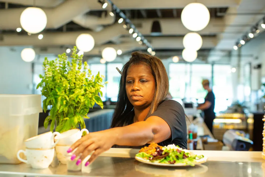 A cafe staff member reaches for a shaker