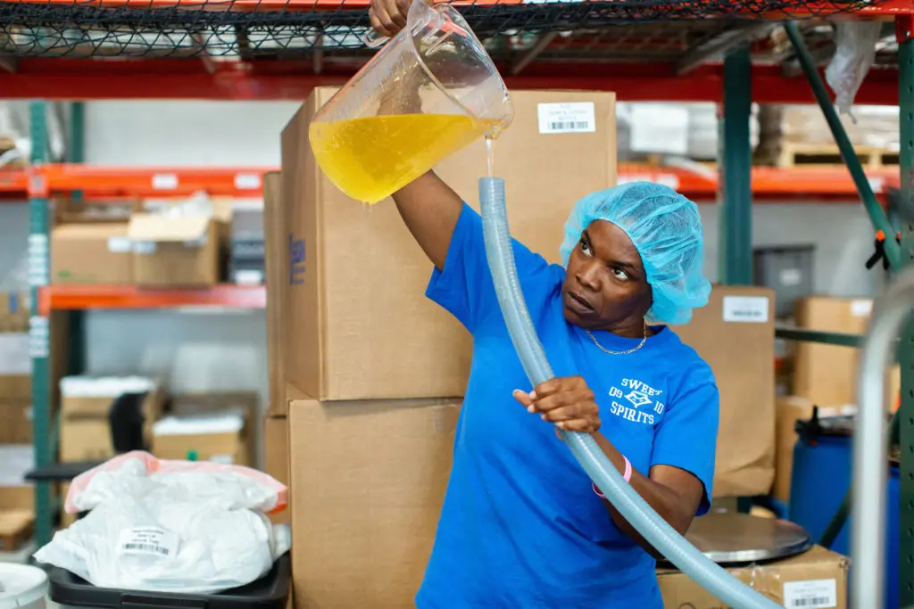Thistle Staff worker pours a container of soap into a hose