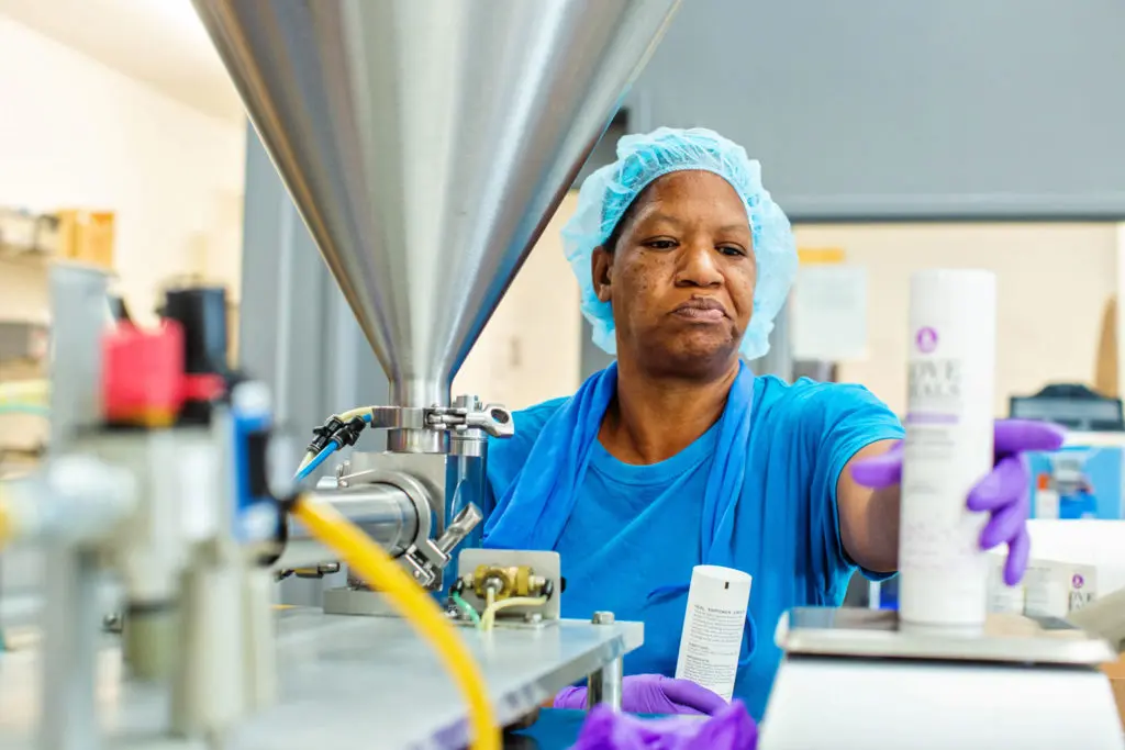 A Thistle Farms staff member weighs a bottle
