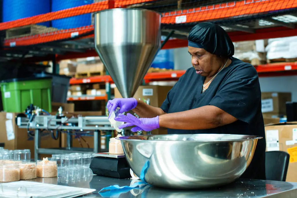A woman pours ingredients into a jar