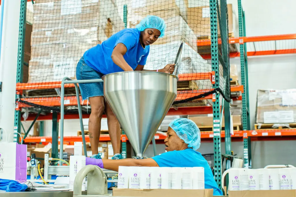 Two women working with a metal funnel