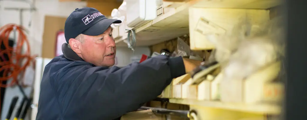 A man looking for hardware on shelf in garage