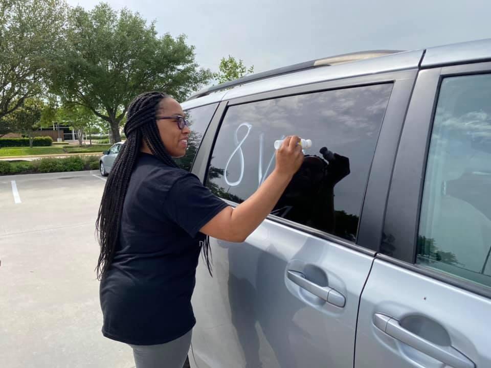 A woman writing on a car window