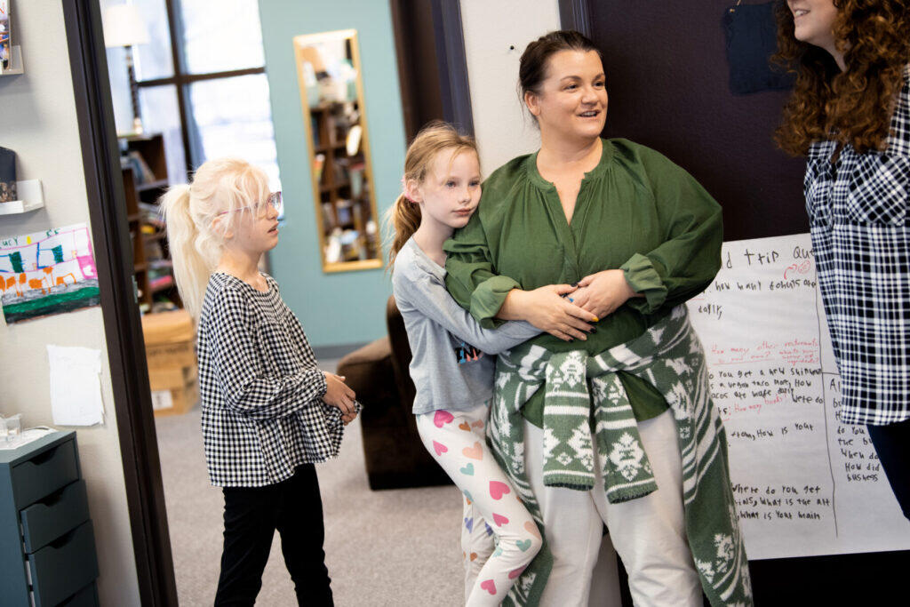 A child hugs a woman engaged in a discussion